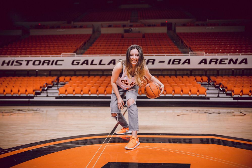 Basketball player poses on orange court in historic Gallagher-IBA Arena.