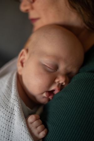 A sleeping baby rests on his mother's shoulder