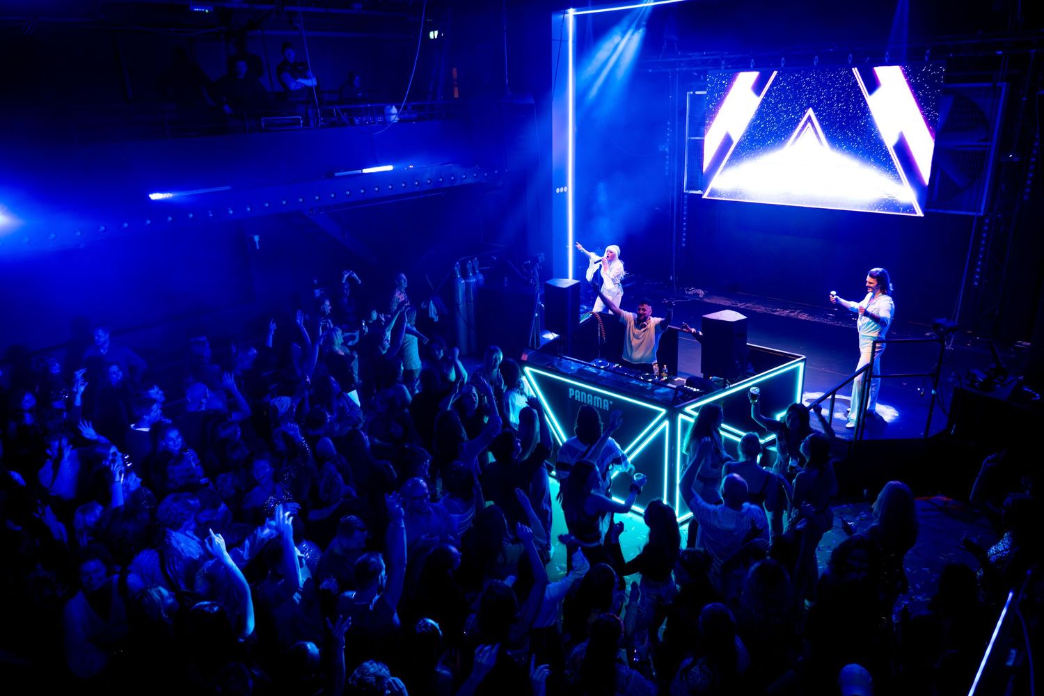 Large concert crowd illuminated by blue stage lights during live performance.
