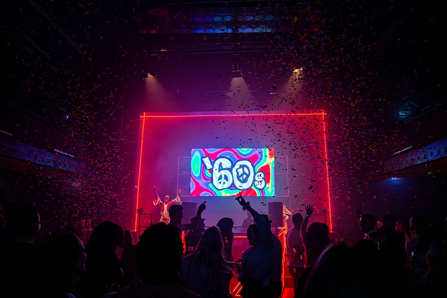 Concert venue with red neon lighting and silhouetted crowd.