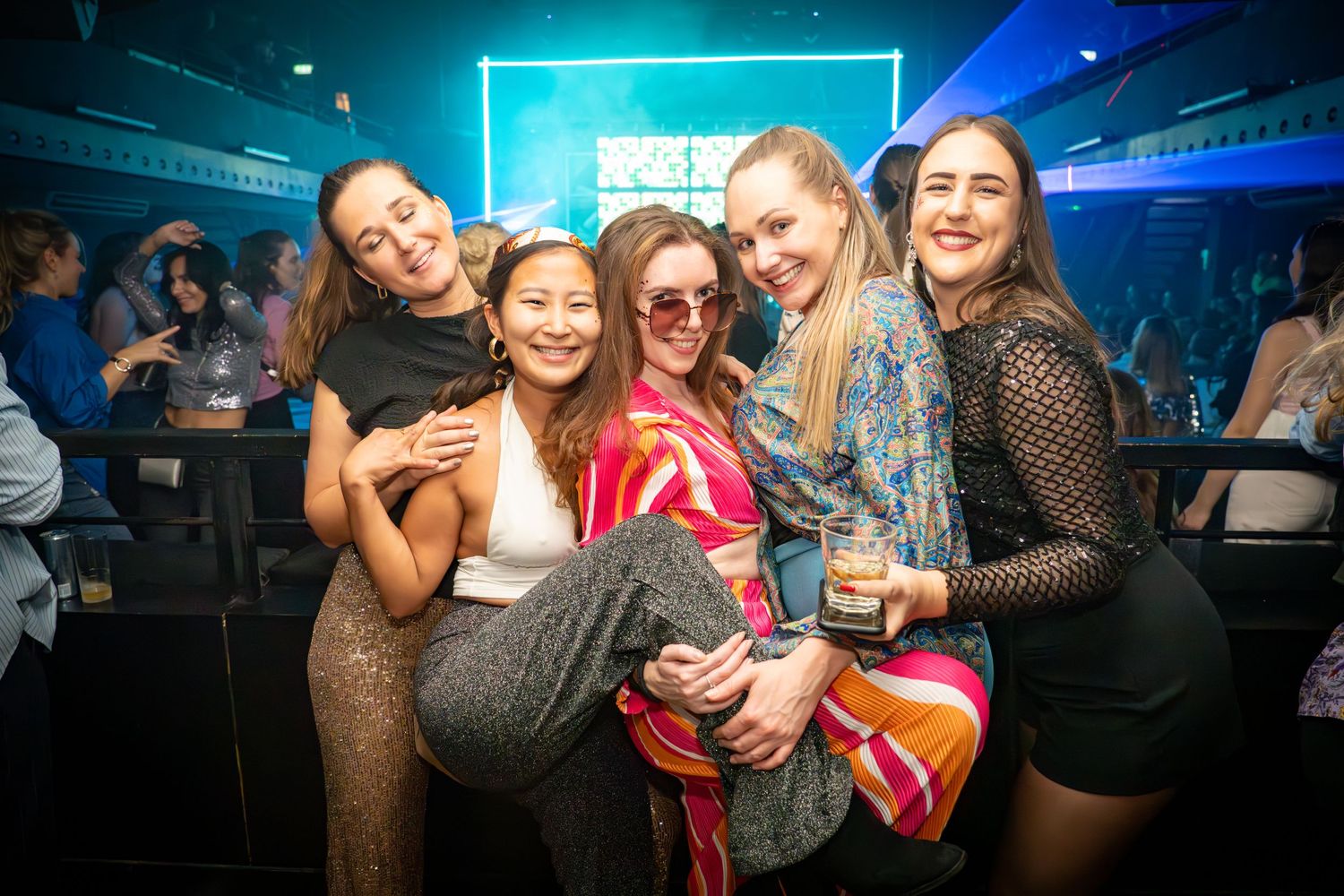 Nightclub crowd enjoying a party with blue lighting and energetic atmosphere.