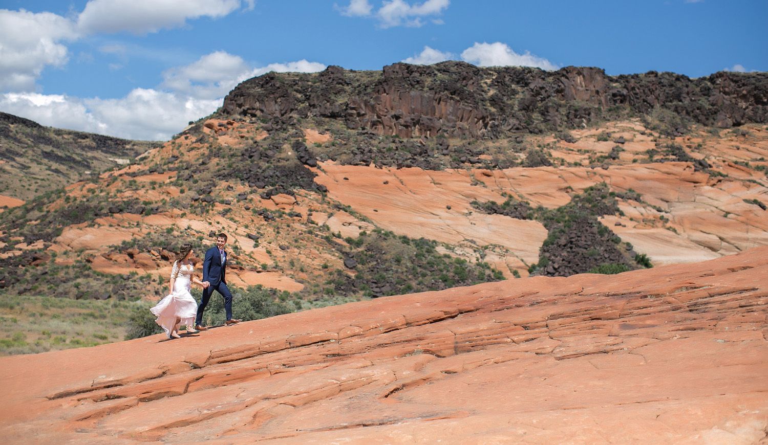 Bride and groom walking on red rocks in Snow Canyon State Park, UT