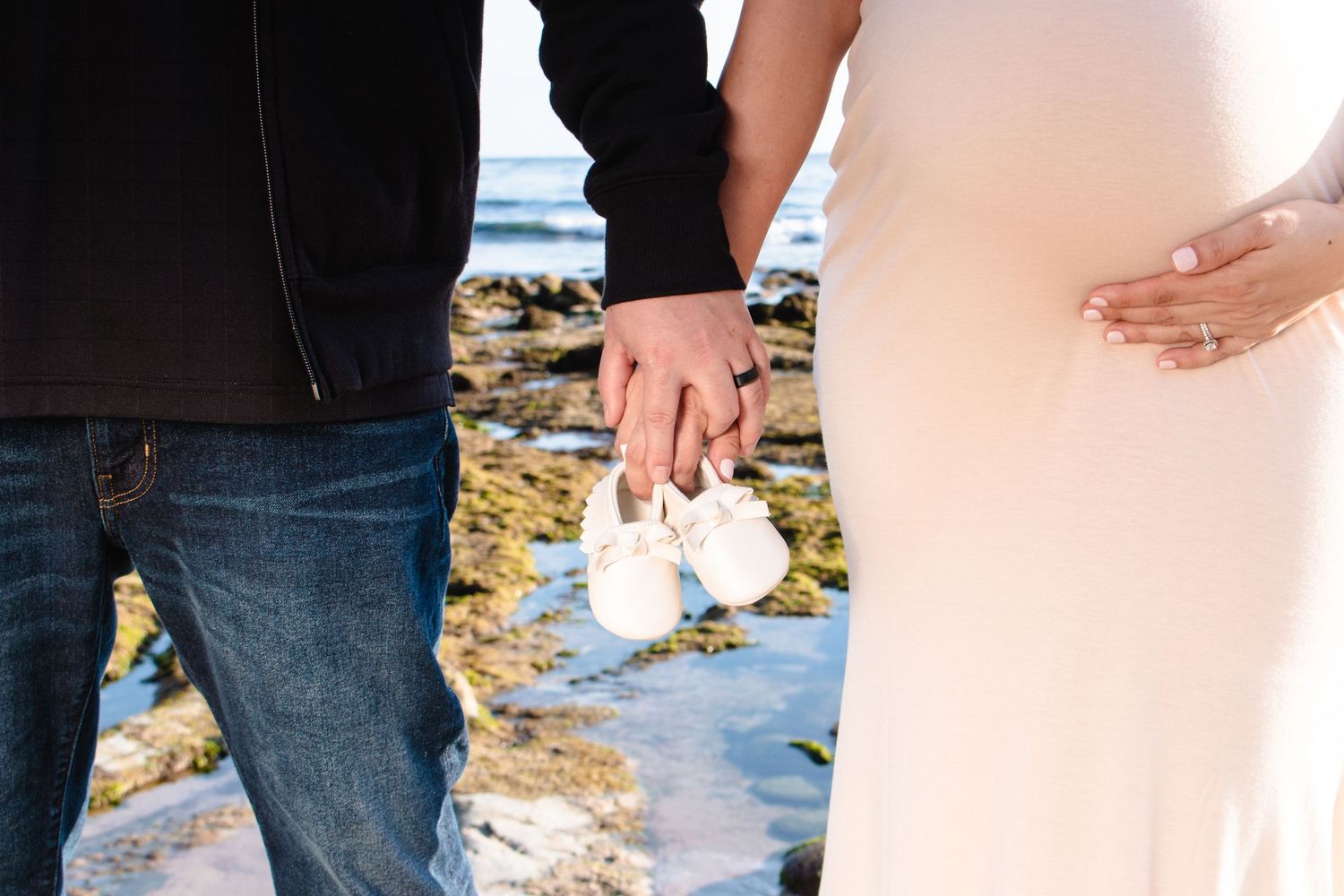 Maternity session at Laguna Beach holding baby shoes