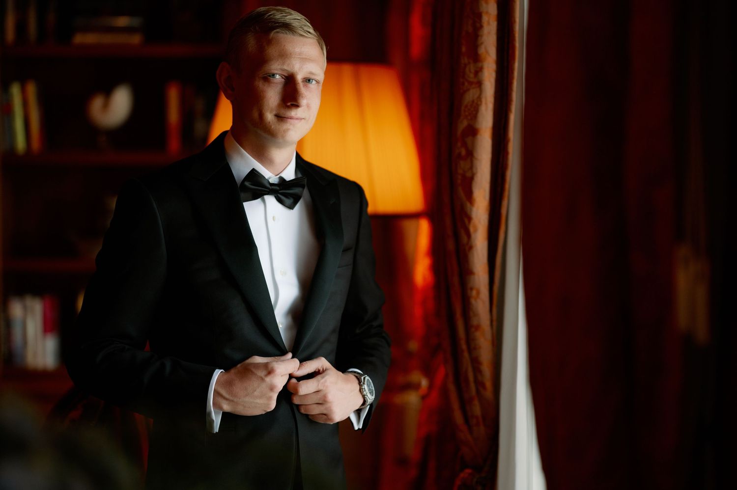 A sophisticated portrait with dramatic lighting and red accents in the background.
