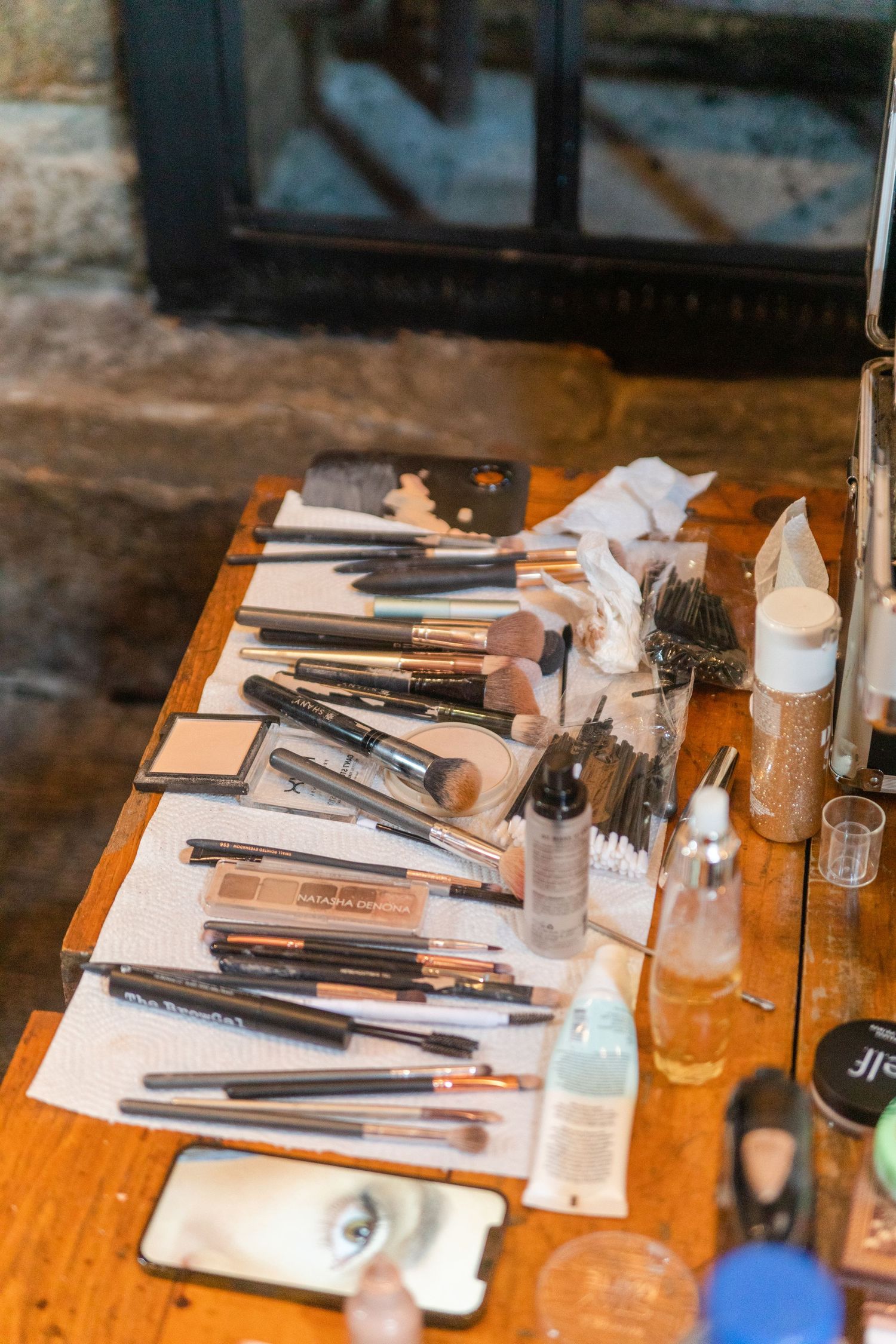 Wedding makeup station with brushes and cosmetics arranged on a wooden table.