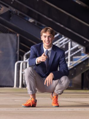 senior boy pointing with orange track shoes