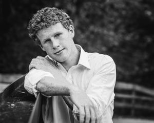 senior boy black and white portrait leaning on railing