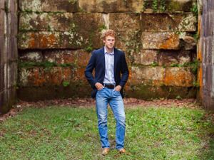 senior boy with red hair in front of stone wall