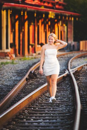 senior girl on train track fixing hair at sunset