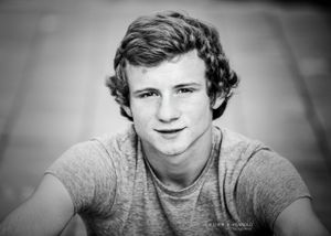 high school senior boy sitting for back and white portrait in tee shirt