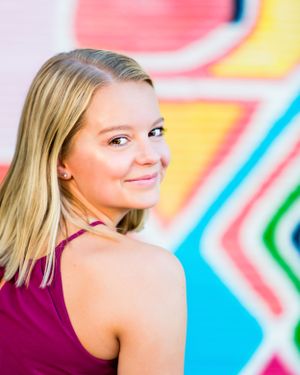 high school senior girl looking over shoulder in front of colorful graphic mural