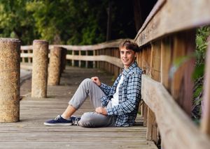 senior boy sitting on boardwalk