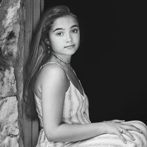 black and white of girl leaning on stone wall with long dark hair