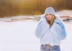 girl in blue fur coat back lit at sunset