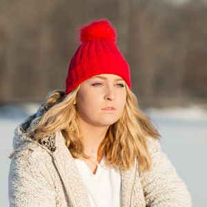high school senior girl in red ski hat and white coat on ice