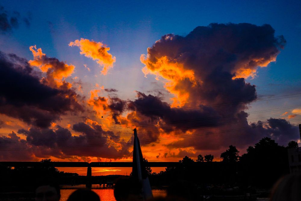 Dramatic orange sunset silhouettes a bridge against fiery clouds.