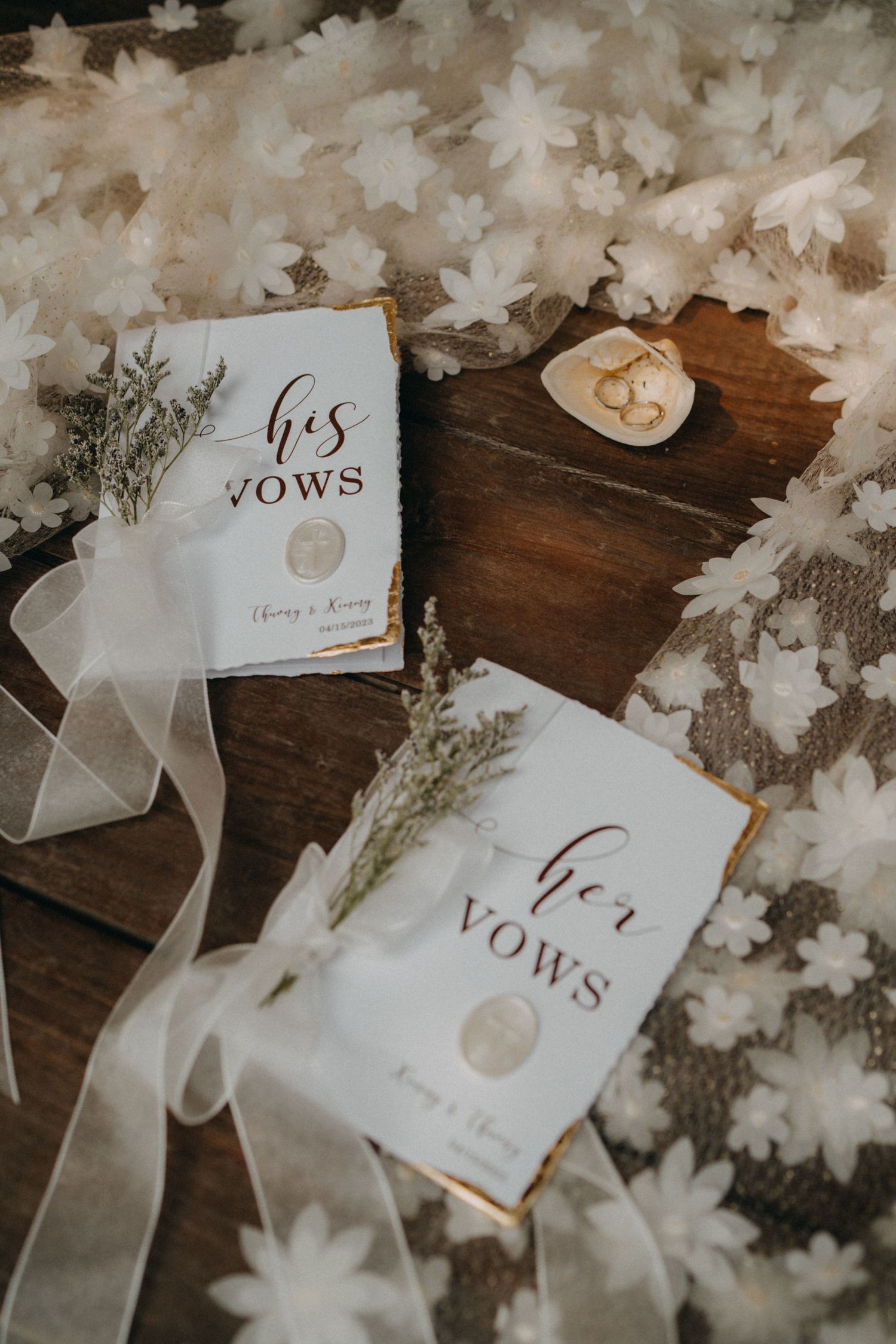 Elegant his and her wedding vow books with rings and white floral decor.