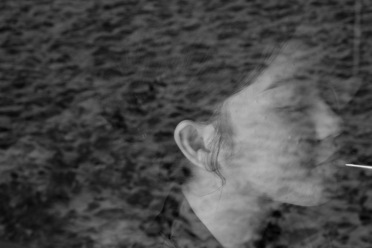 Artistic blurred black and white portrait of a man with motion blur effect outdoors.