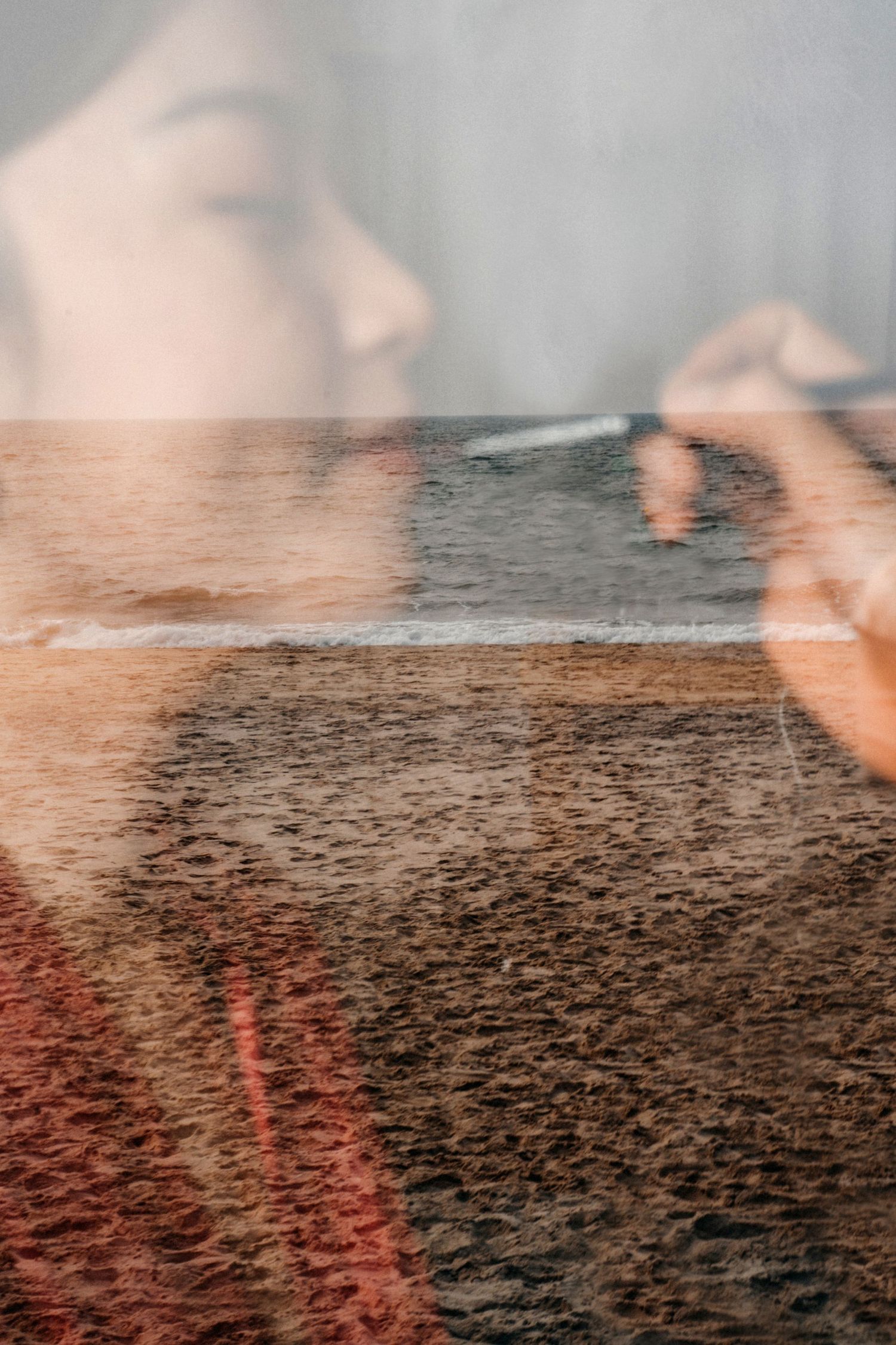 Artistic double exposure of woman's profile with sandy beach landscape.