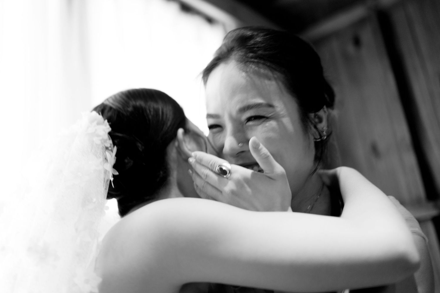 Emotional black and white photo of bride hugging guest at wedding.