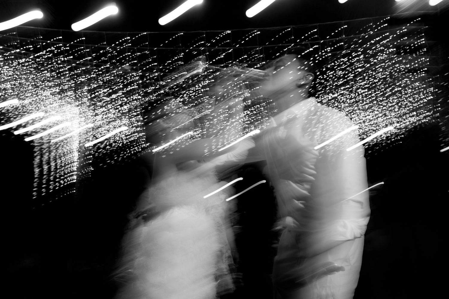 Blurred motion black and white photo of couple dancing at a wedding reception.