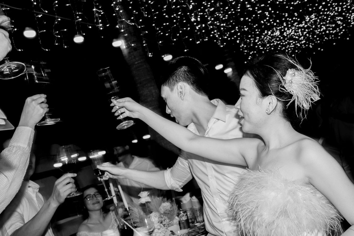 Bride and groom toasting champagne with guests at lively outdoor wedding reception.