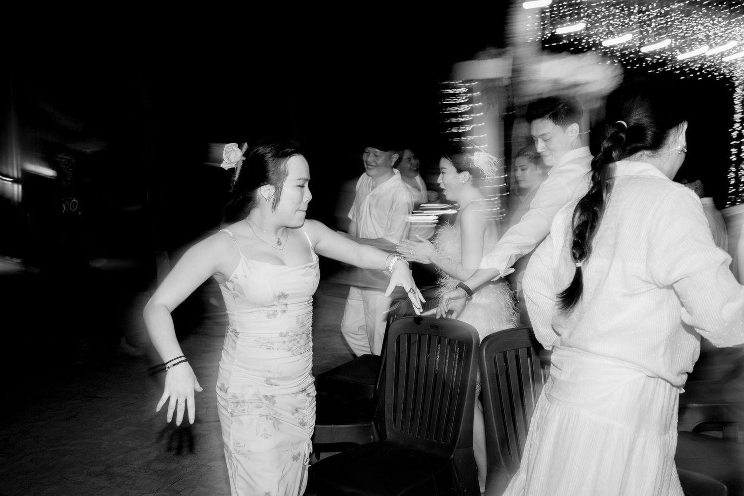 Black and white photo of guests dancing energetically at an outdoor wedding reception celebration.
