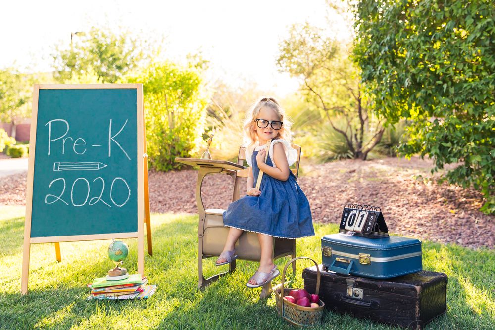 Back to school photo featuring chalkboard sign and vintage props in garden setting.