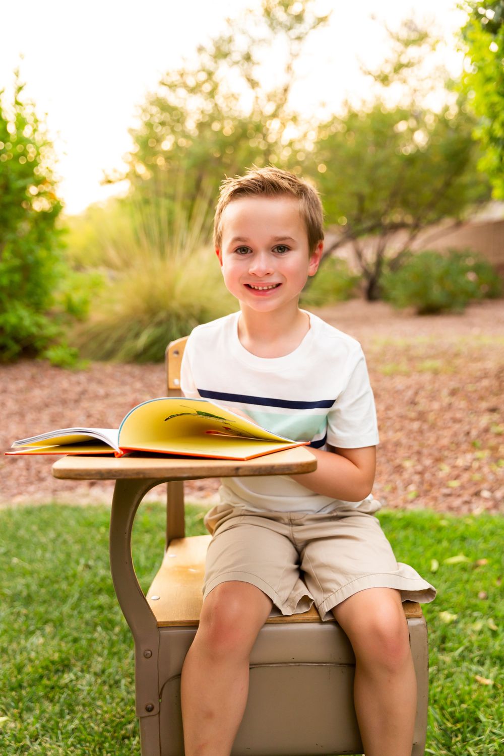 Student sitting on outdoor chair with schoolbooks during golden hour photography session.