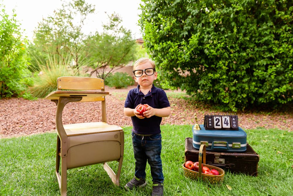 Small child stands by vintage props and countdown blocks in garden photo setup.