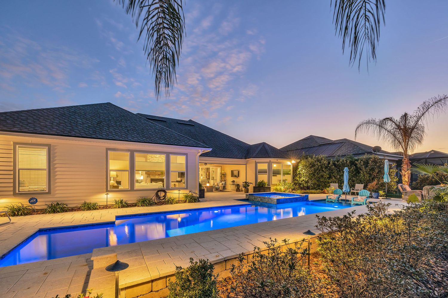 Twilight image of back on home with a pool