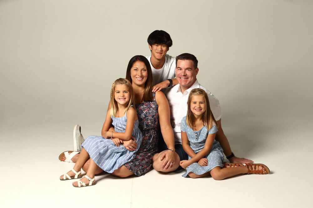 Studio portrait of a loving family wearing coordinated blue and white outfits against neutral backdrop.