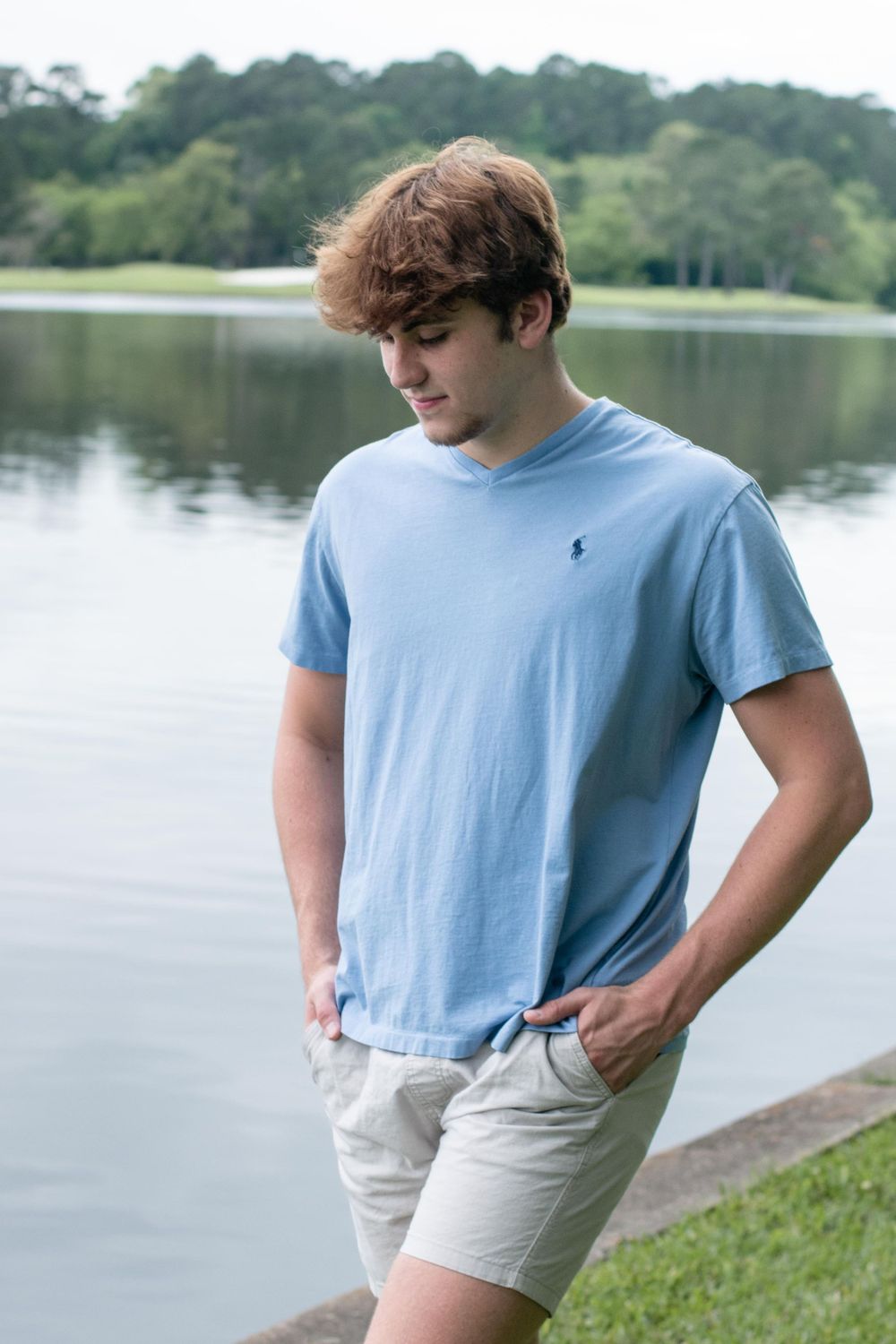 Casual summer portrait by the lake wearing light blue polo and khaki shorts.