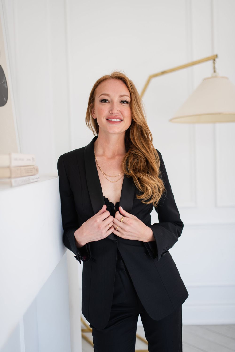 Professional woman in black blazer and pants smiling in bright white modern interior.