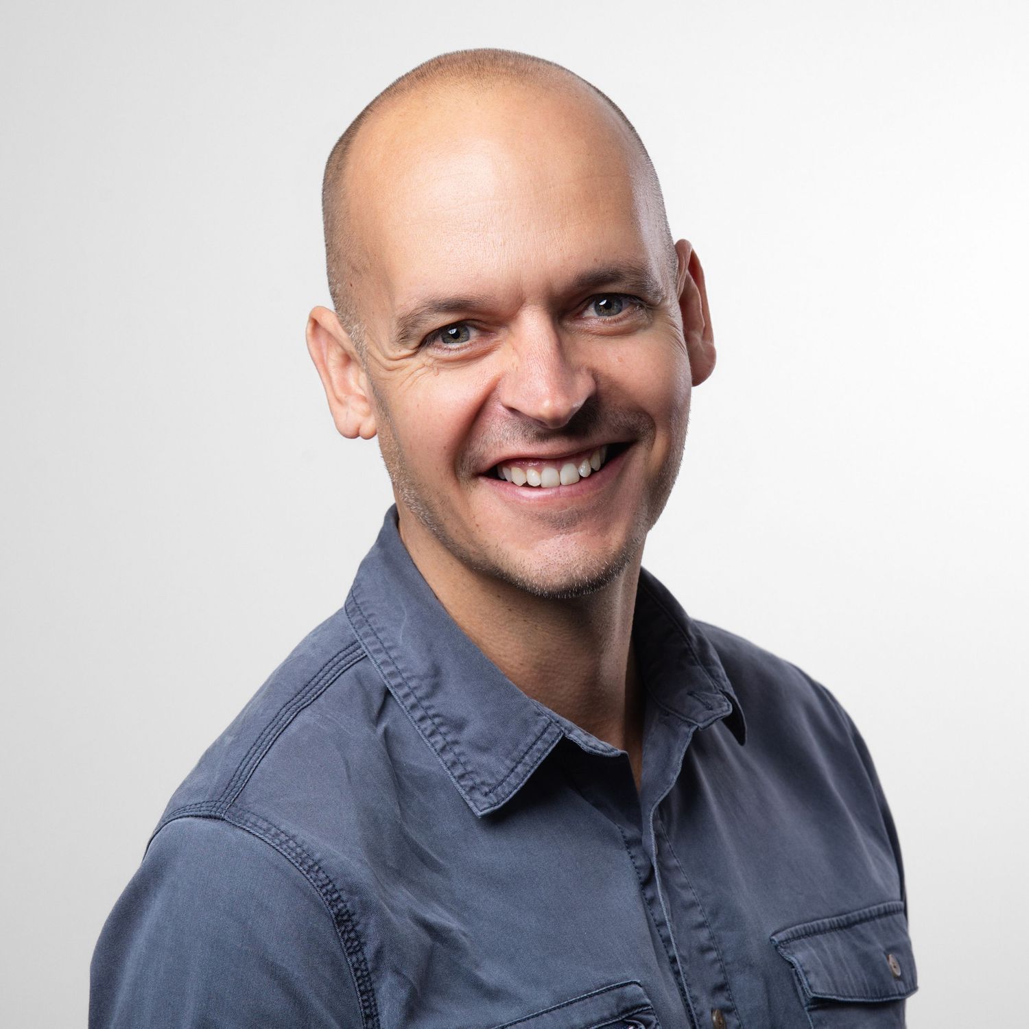 Smiling man in a blue denim shirt against a white background, professional corporate headshot photography Southampton