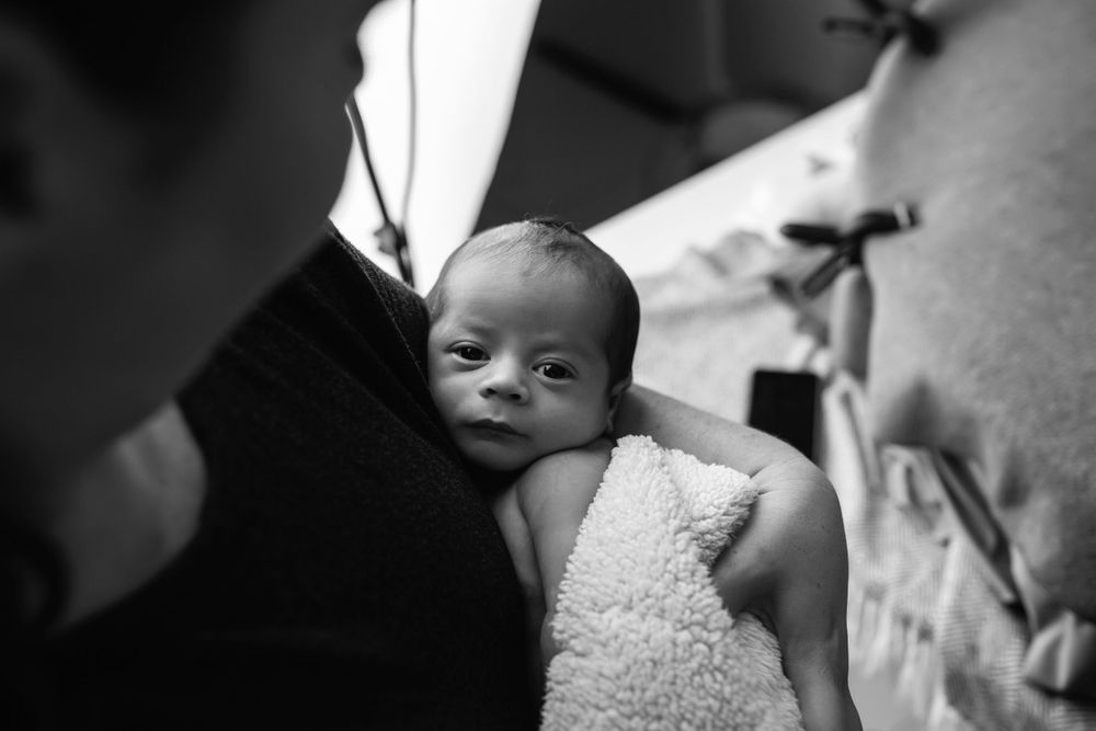 Black and white portrait of newborn baby wrapped in soft blanket.