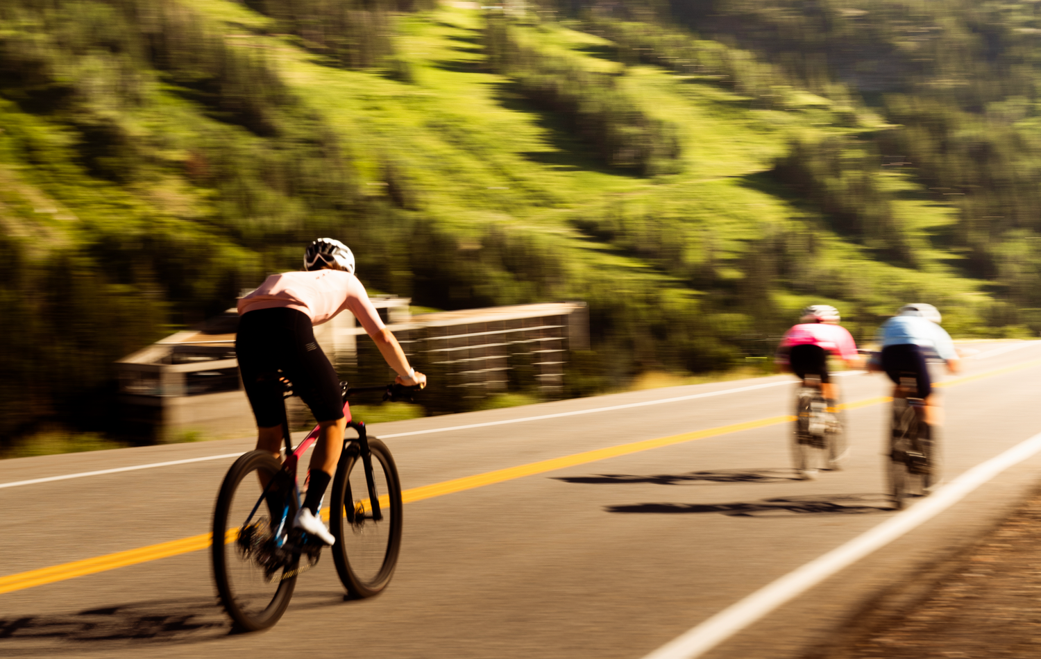 Cyclists riding along a scenic mountain road on a sunny afternoon.