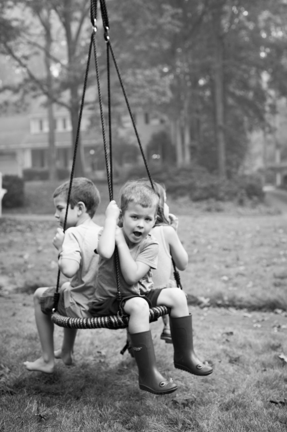 Vintage black and white photo of two children sitting on a tree swing.