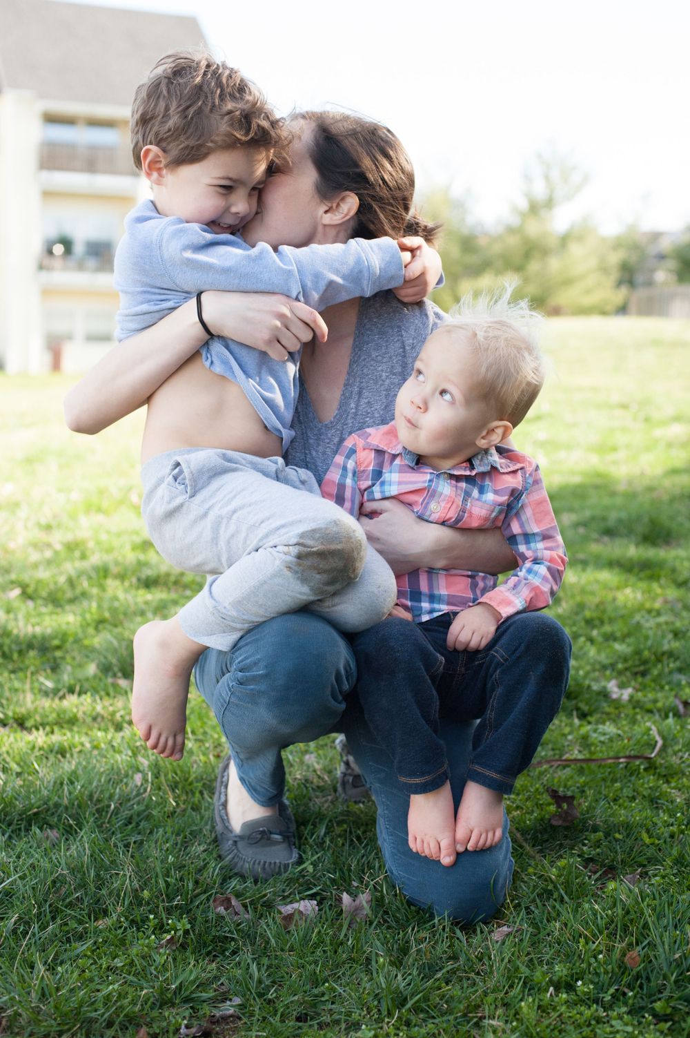 Family embracing outdoors on a sunny day in a grassy field.