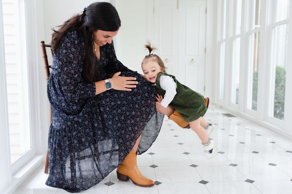 A playful interaction between parent and child in a bright, sunlit room with white walls.