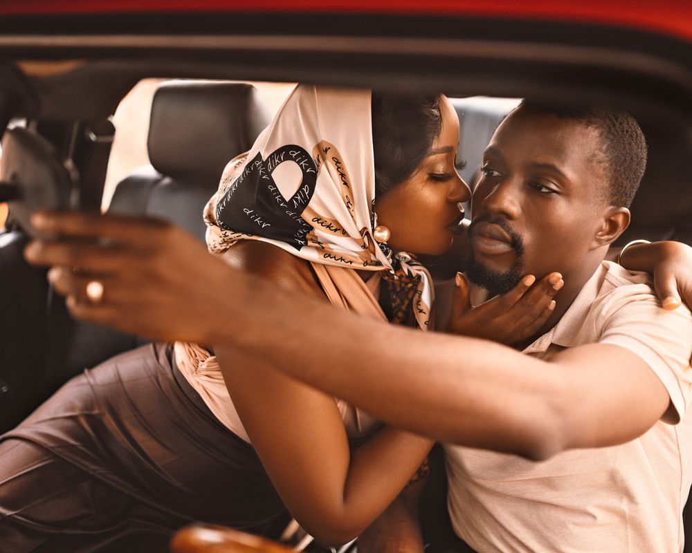 A couple sharing an intimate moment inside a car with warm lighting.