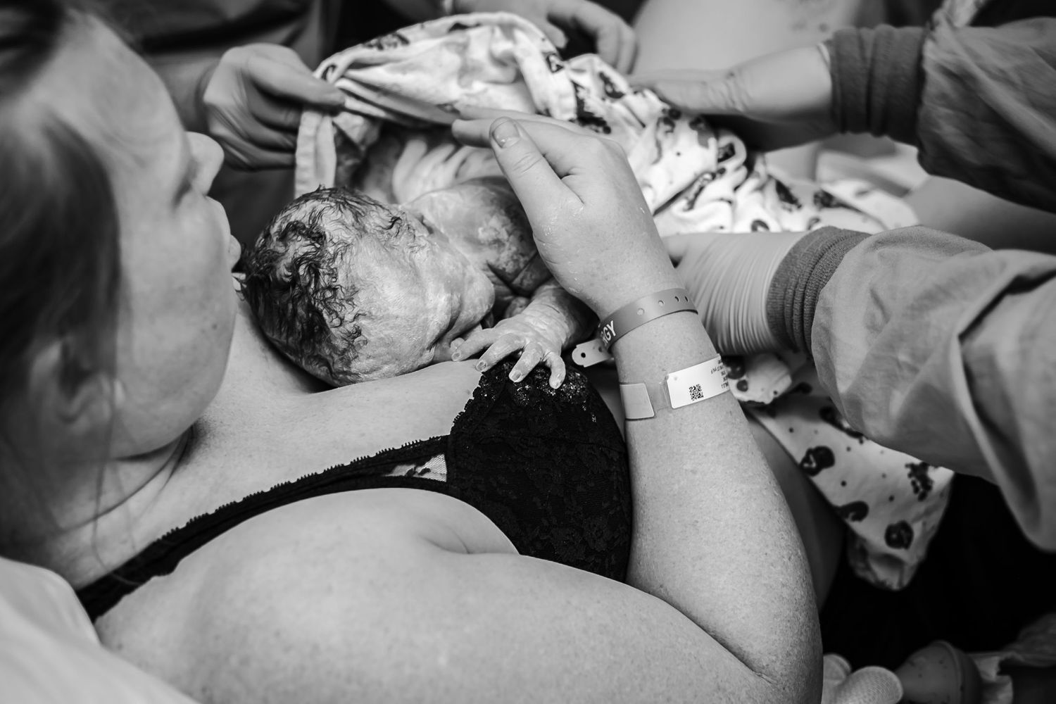 Mom holding her newborn just after birth while the nurses wrap a blanket over the baby at UnityPoint Health.
