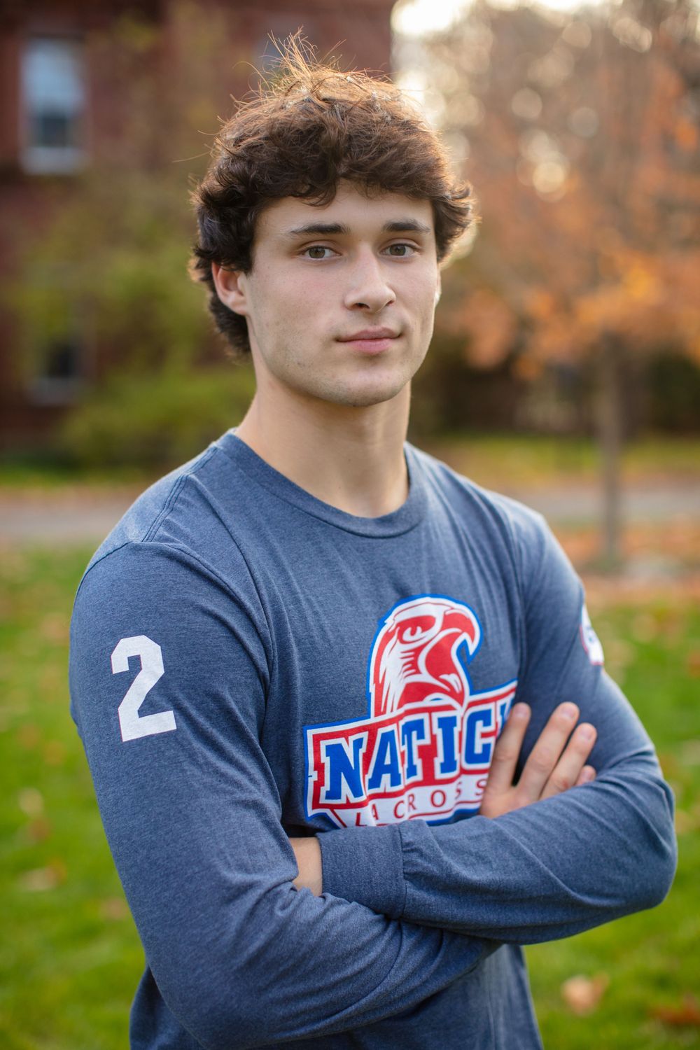 Athlete in blue long-sleeve shirt with number 2 and team logo poses outdoors.