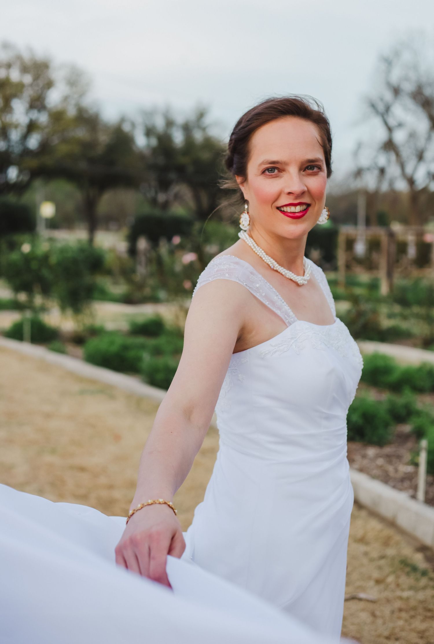 Elegant white wedding dress twirls against natural outdoor backdrop.