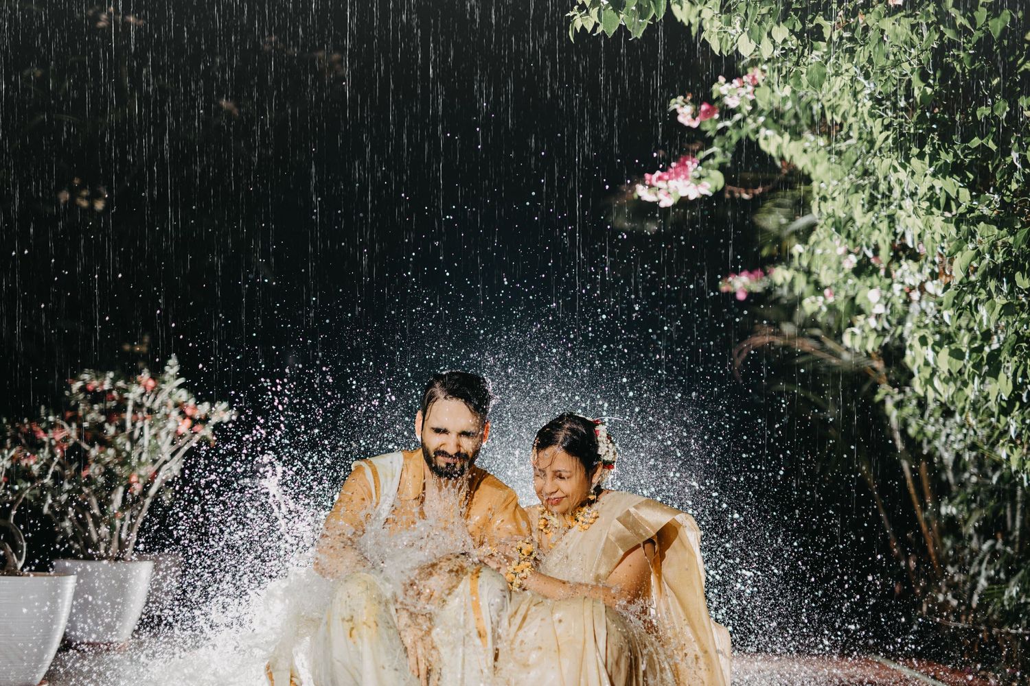 Water splashing dramatically during outdoor photoshoot with greenery backdrop.