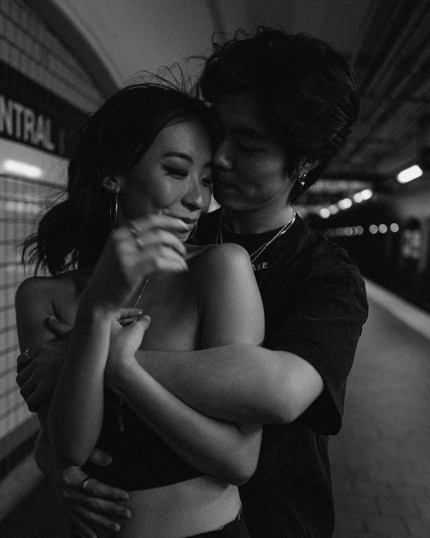 Intimate moment between couple in black and white at subway station.