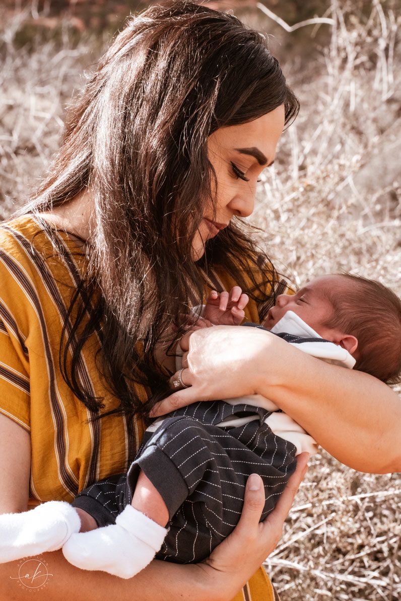 Intimate moment captured in warm light as a mother cradles and feeds her newborn.