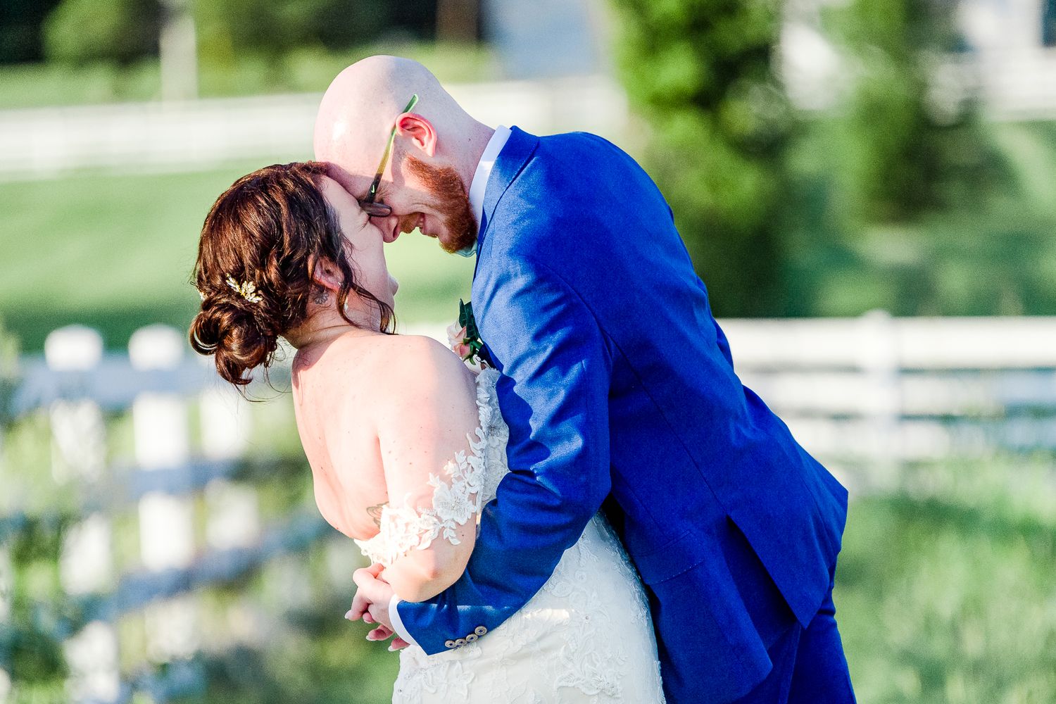 Romantic wedding couple embraces outdoors with the groom in a bright blue suit and bride in lace dress by Stephanie Coulter Photography