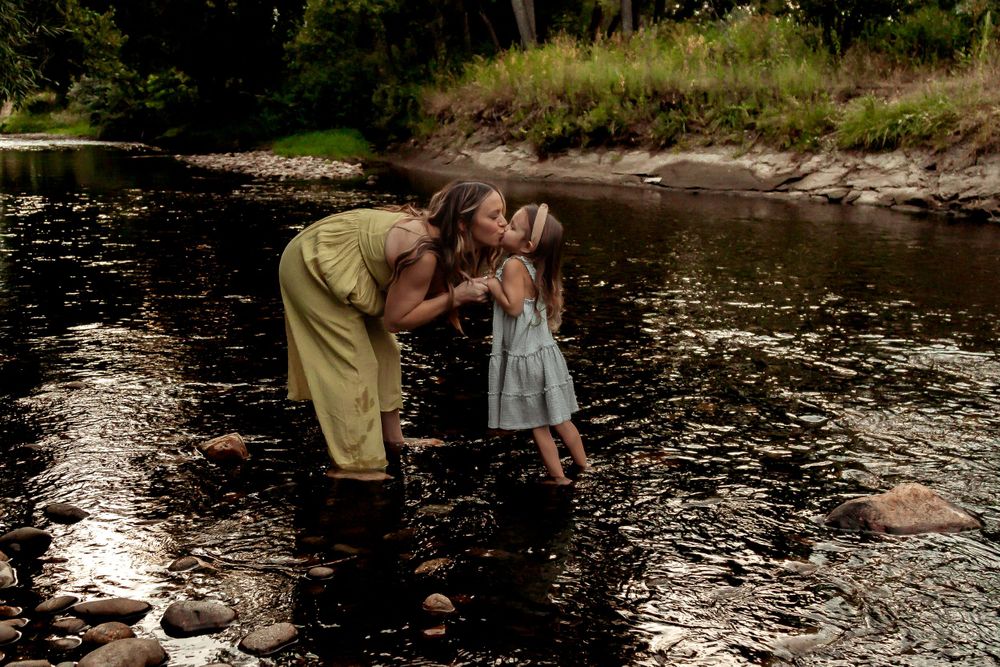 A parent and child share an intimate moment while playing in a stream. Denver Family Photography.