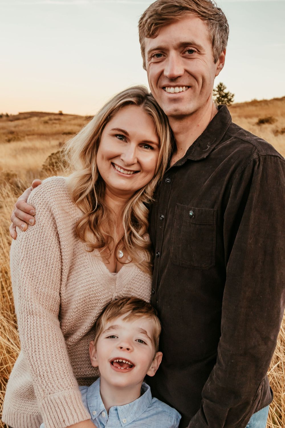 Happy family portrait with young child in autumn field at sunset. Denver Family Photography.